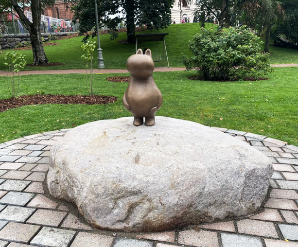 Pieni pronssinen patsas puistossa kiven päällä